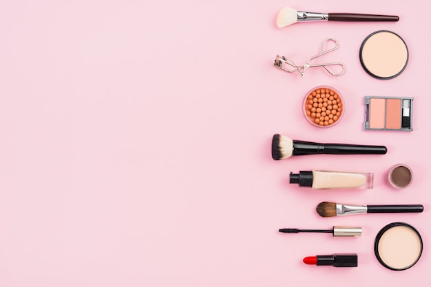 Maquillaje y productos de belleza estética sobre fondo rosa.