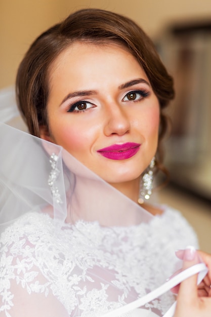 Maquillaje retrato de hermosa novia en vestido de novia blanco brillante. Preparación final de la mujer recién casada para la boda.