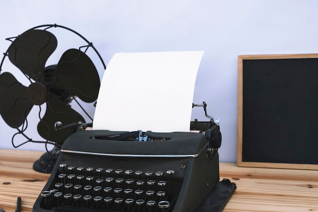 Foto gratuita máquina de escribir entre pizarra y ventilador