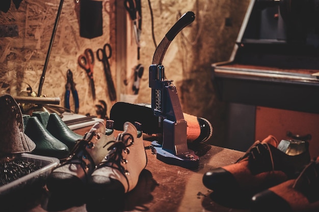 Máquina herramienta sobre la mesa con zapatos para hacer agujeros para cordones en el taller del zapatero.