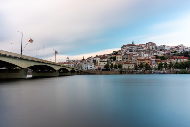 Mar con un puente rodeado por la ciudad de Coimbra bajo un cielo nublado en Portugal