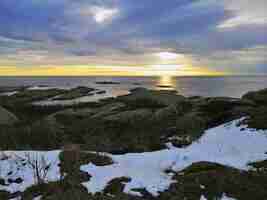 Foto gratuita mar rodeado de rocas bajo un cielo nublado durante la puesta de sol en rakke en noruega