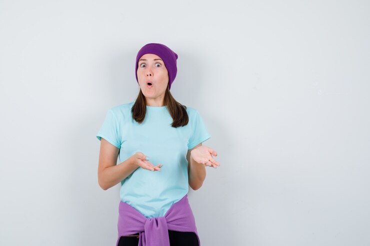 Foto gratuito maravillosa dama fingiendo mostrar algo, abriendo la boca en blusa, gorro y luciendo aterrorizada. vista frontal.