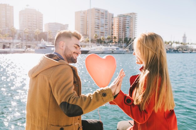 Maravillosa joven pareja sentada tiernamente en el paseo marítimo