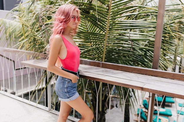 Maravillosa mujer joven en traje de verano con estilo posando sobre fondo exótico.