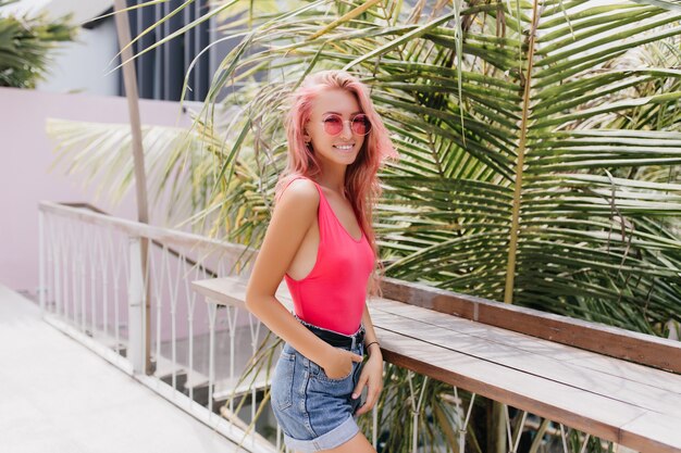 Maravillosa mujer joven en traje de verano con estilo posando sobre fondo exótico.