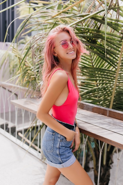 Maravillosa mujer joven en traje de verano con estilo posando sobre fondo exótico.