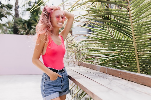 Maravillosa mujer joven en traje de verano con estilo posando sobre fondo exótico.