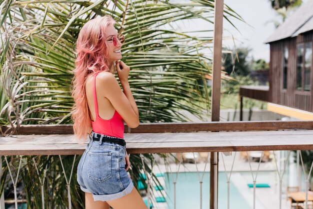 Maravillosa mujer joven en traje de verano con estilo posando sobre fondo exótico.