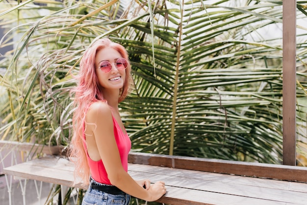 Maravillosa mujer joven en traje de verano con estilo posando sobre fondo exótico.