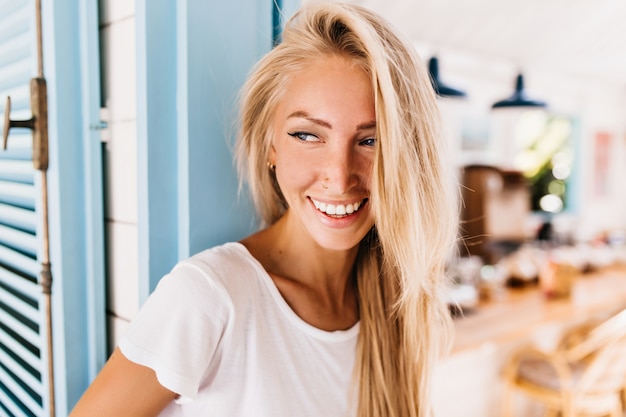 Maravillosa mujer ligeramente bronceada en jeans retro posando con una sonrisa positiva.