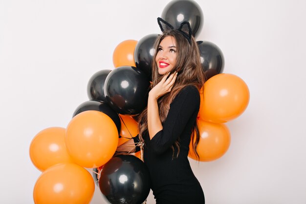 Maravillosa mujer de pelo largo soñadora posando con globos de halloween