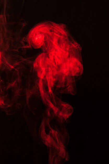 Maravilloso humo de humo rojo extendido sobre fondo negro