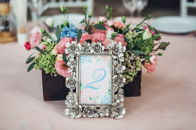 Foto gratuita marco de acero con el número 2 se encuentra ante la caja de madera con flores