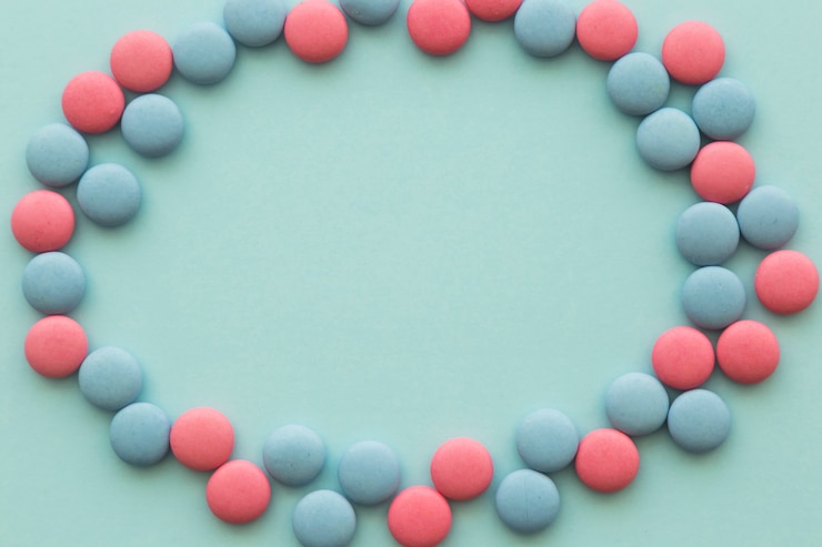 Foto gratuito marco en blanco hecho con caramelos rosados y azules circulares en el contexto coloreado