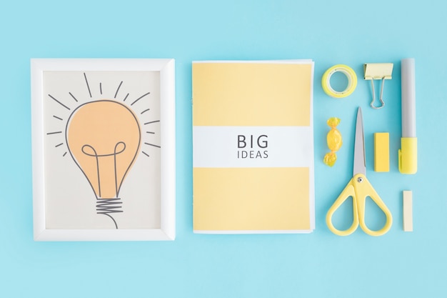Marco de bombilla; libro de grandes ideas y papelería sobre fondo azul