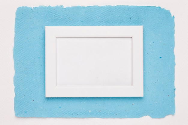 Un marco de borde blanco vacío sobre papel azul sobre fondo blanco.