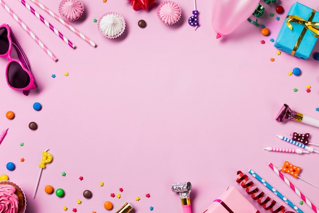 Marco circular en blanco hecho con artículos de fiesta de cumpleaños sobre fondo rosa