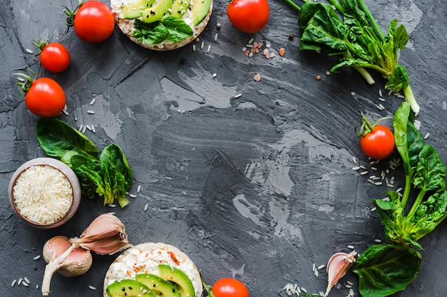 Marco circular hecho con verduras frescas y bocadillos saludables sobre papel tapiz de cemento desgastado