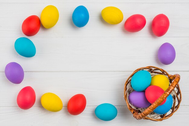 Marco de coloridos huevos de Pascua y cesta en mesa