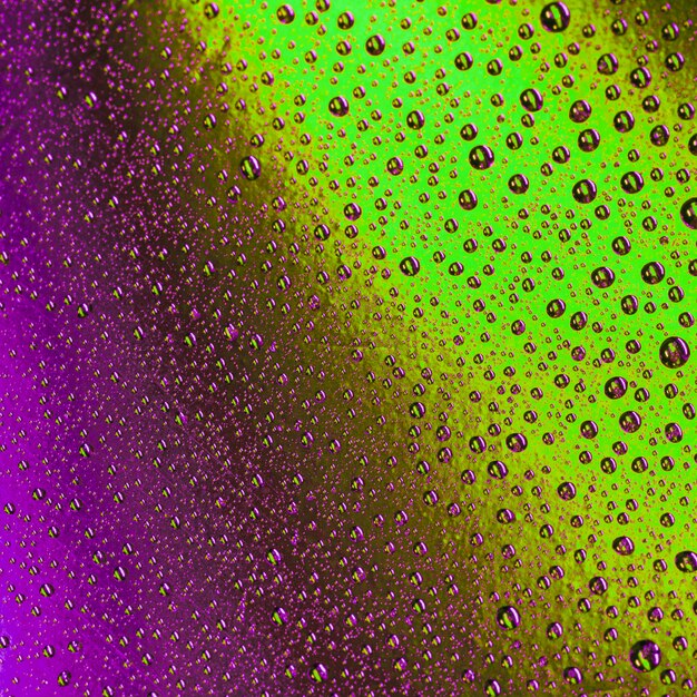 Marco completo de gotas de color púrpura sobre fondo con textura verde