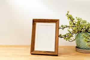 Foto gratuita marco decorativo en blanco sobre mesa de madera