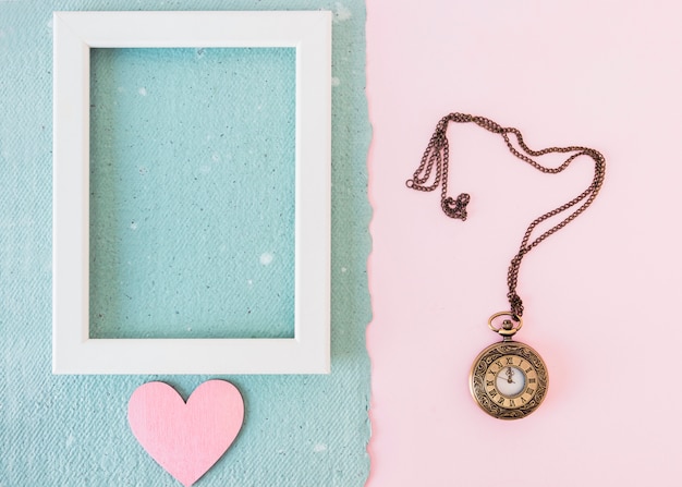 Foto gratuita marco de fotos y adornos de corazón en papel azul cerca del reloj de bolsillo viejo