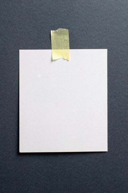 Marco de fotos en blanco con sombras suaves y cinta adhesiva amarilla sobre fondo de papel artesanal negro