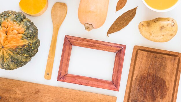 Marco de fotos cerca de verduras y tabla de cortar.