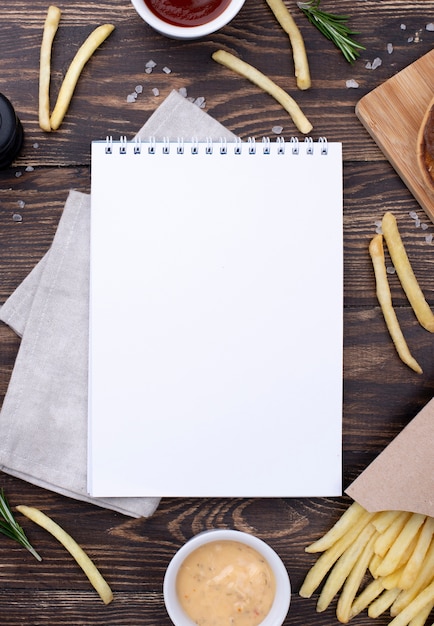 Foto gratuita marco de hamburguesas y papas fritas al lado del cuaderno