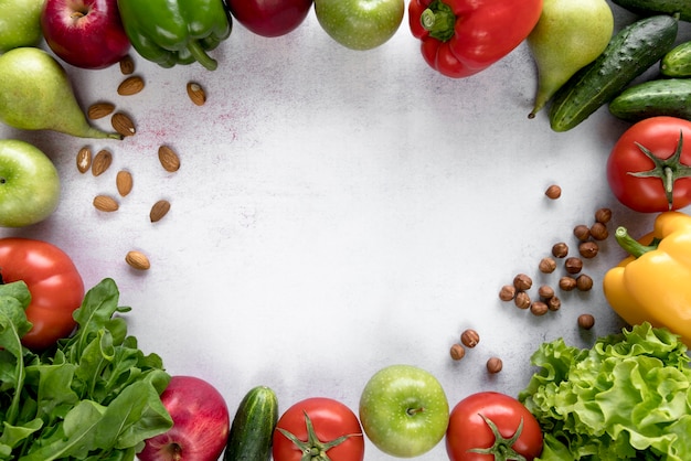 Marco hecho con frutas de colores; Verduras y frutos secos sobre superficie blanca.