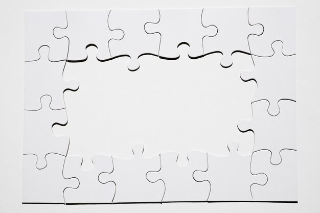 Marco hecho de pieza de puzzle blanco sobre fondo blanco