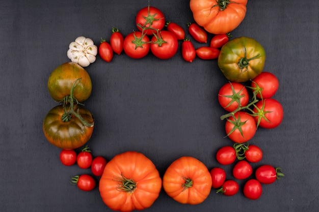 Marco hecho de tomate cherry tomate y ajo vista superior sobre superficie negra