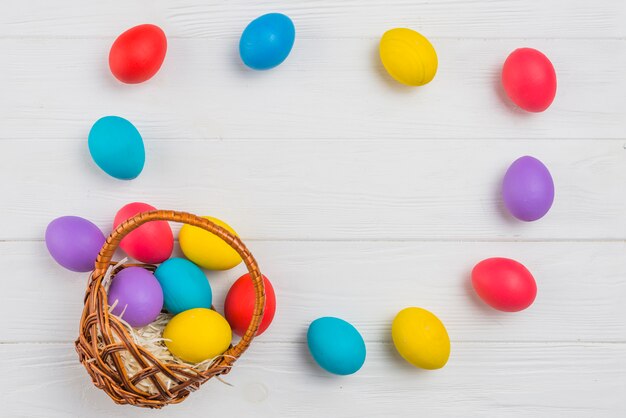 Marco de huevos de Pascua y cesta en mesa de madera