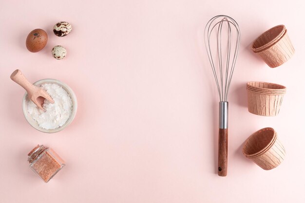 Marco de ingredientes alimentarios para hornear sobre un fondo pastel suavemente rosa Cocina plana con espacio de copia Vista superior Concepto de horneado