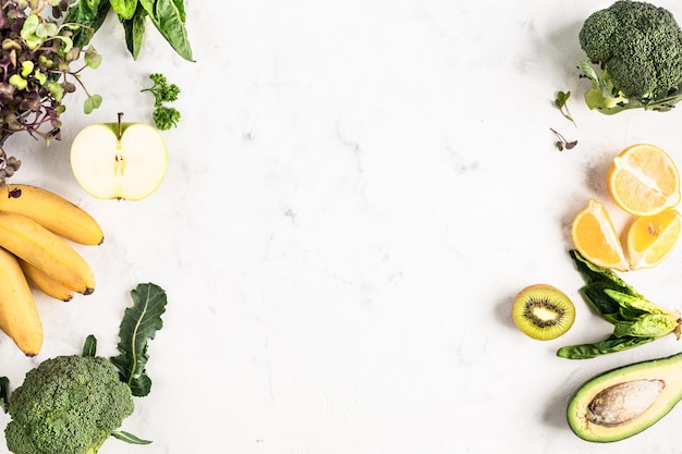 Marco de ingredientes para un batido verde de verduras y frutas o para una ensalada fresca sobre un fondo blanco, vista superior