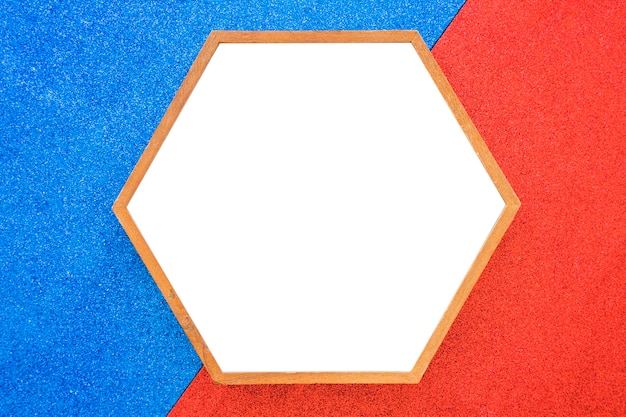 Un marco de madera hexagonal vacío sobre fondo rojo y azul