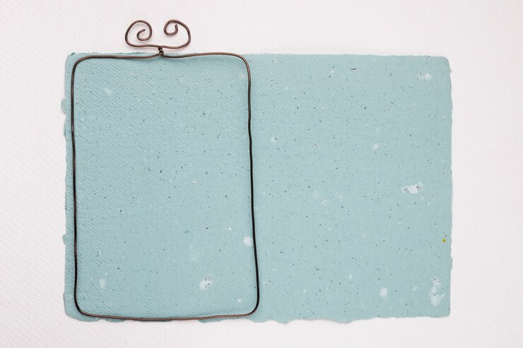 Foto gratuito marco metálico sobre papel con textura azul sobre fondo blanco.