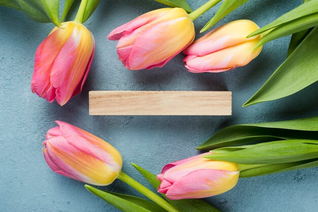 Marco plano de tulipanes con etiqueta de madera