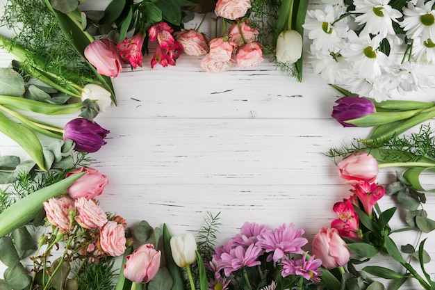 Marco realizado con diferentes tipos de hermosas flores en superficie de madera.