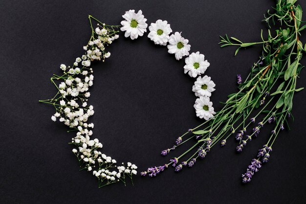 Marco redondo hecho de pequeñas flores blancas sobre fondo negro