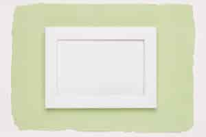 Foto gratuita marco vacío blanco sobre fondo de papel verde