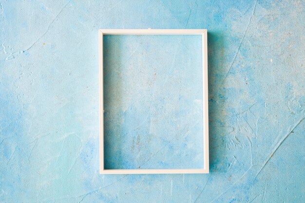 Un marco vacío con borde blanco en la pared pintada de azul