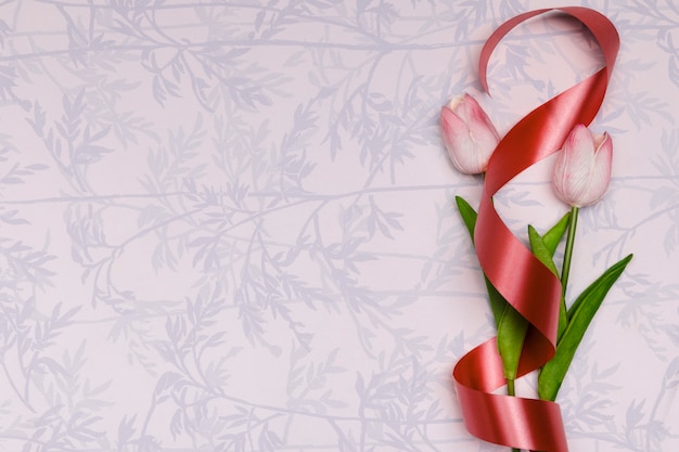 Foto gratuita marco de vista superior con tulipanes y cinta roja