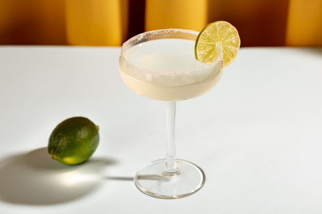Margarita cocktail en platillo de vidrio con limón en mesa blanca