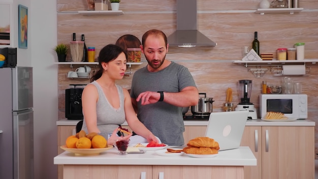 Marido apresurarse en el trabajo mientras toma un bocado de pan tostado con mantequilla durante el desayuno. Hombre estresado tarde apresurándose nervioso corriendo rápido a la reunión, prisa para trabajar, tarde para la cita