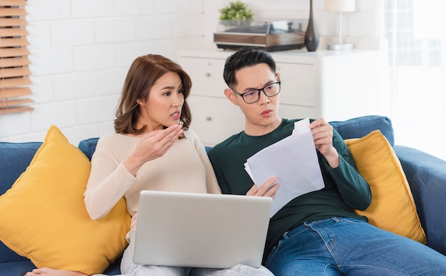 Foto gratuita marido asiático serio comprobación analizando facturas de servicios públicos de declaración sentados juntos en casa.