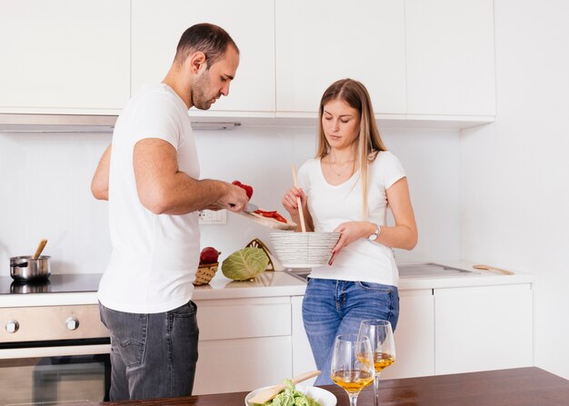 Marido ayudando a su esposa para cocinar comida en la cocina.