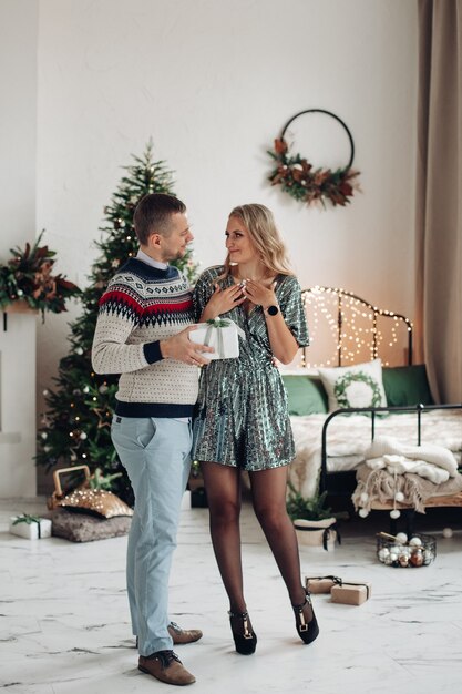 Marido cariñoso dando a su esposa regalo de Navidad. Bella mujer sorprendida al recibir un regalo de su marido.