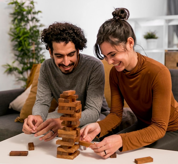 Marido y mujer jugando un juego de torre de madera en casa